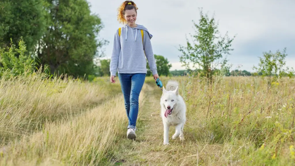Young woman walking her dog outdoors as part of a mindful wellness routine after a spiritual retreat.